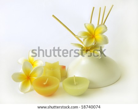 Close-up of colorful candles and stick diffuser on white background
