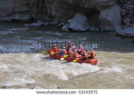 Group of tourists fighting with strong stream of mountain river.