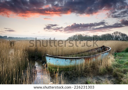 Beautiful sunset over an old rusty fishing boat washed up in reeds on the shores of Poole Harbour in Dorset