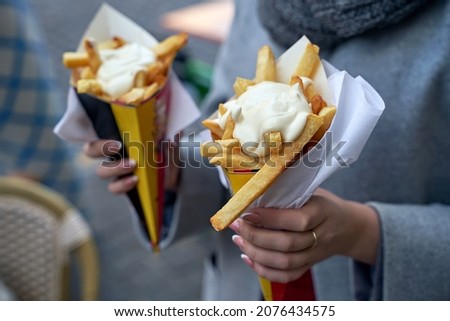 Belgian frites or french fries with mayonnaise in Brussels, Belgium. Female tourist holds two portions of fries in hands in the street. Stock fotó © 