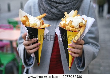Belgian frites or french fries with mayonnaise in Brussels, Belgium. Female tourist holds two portions of fries in hands in the street. Stock foto © 