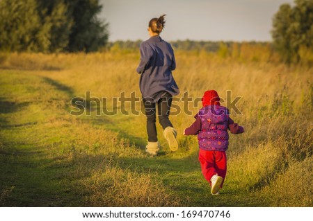 Mother and daughter running: Mother and daughter running on a field, playing
