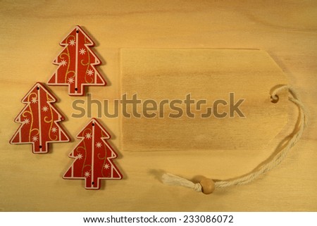 Empty tag with three Christmas decorations on red background. Three Christmas decoration with wooden price tag