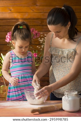 Mother and her happy daughter cooking and baking.