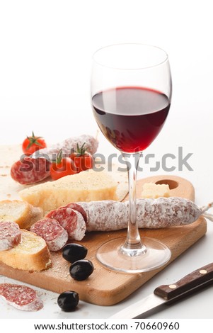 Wineglass with red wine and assortment of cheese and fruits on white background