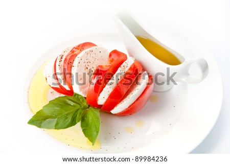 Tomato and mozzarella slices with basil leaves on white background