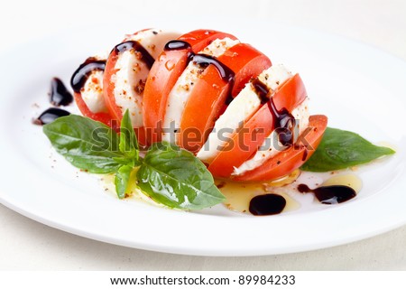 Caprese salad Tomato and mozzarella slices with basil leaves on white background