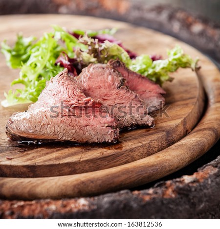 Roast beef on cutting board with lettuce