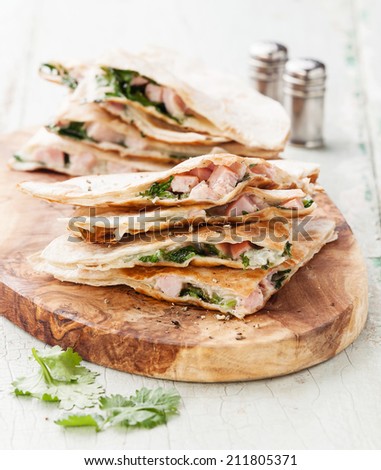 Quesadilla with cheese, meat and vegetables on olive wood cutting board