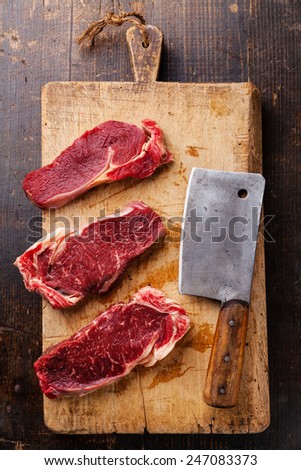 Raw fresh meat Ribeye steak entrecote and meat cleaver on cutting board on wooden background