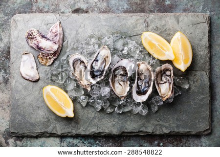 Opened Oysters on stone plate with ice and lemon