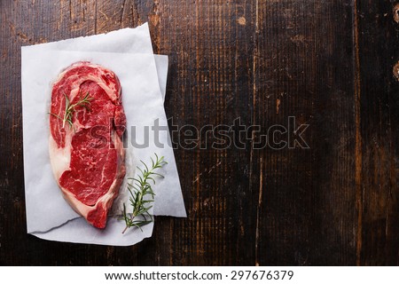 Raw fresh marbled meat Black Angus Steak and rosemary on dark wooden background