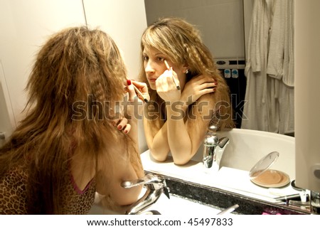 Beautiful Young Woman Making Up with Eye Pencil in front of the Dresser