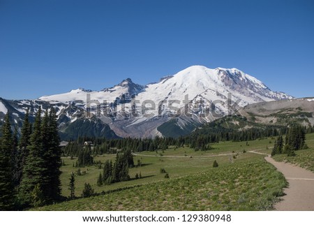 A view of Mt. Rainier in Mt. Rainier National Park from the Sourdough Ridge Trail overlooking the Sunrise visitorÃ¢Â?Â?s center with clear blue sky.