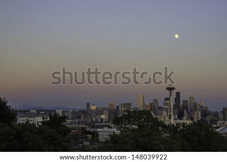 The iconic view of the Seattle skyline at sunset from Kerry Park with full moon overhead.