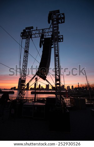 A speaker array hanging for an outdoor concert at sunset.
