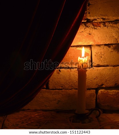 Single burning candle in gothic castle background
