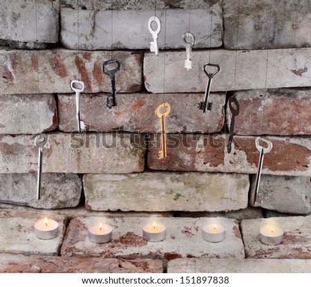 Five burning tea candles with old hanging keys on stone wall background 2