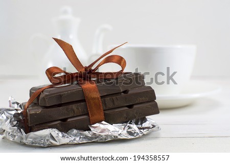 Still life with chocolate pieces with orange bow and defocused porcelain tea set