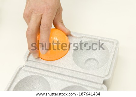 hand holding orange plastic dye-filled anti-theft baseball