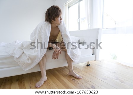 man sitting on bed looks at outside of window