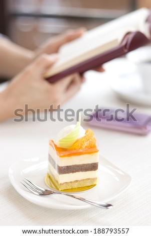 Orange cake and woman reading a book