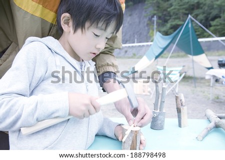 boy learning wooden work in front of tent