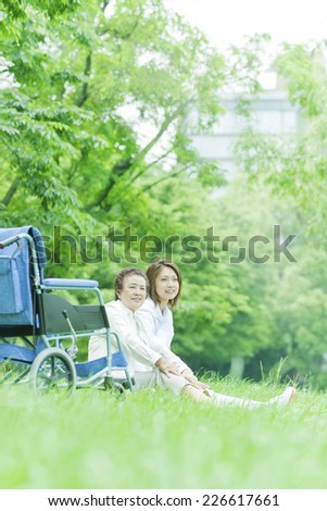 Nurse and senior woman sitting on lawn