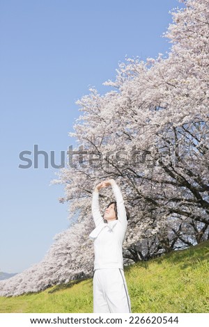 Oriental cherry tree rows and a stretching middle-aged woman