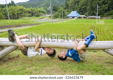 Two boys hanging down a log