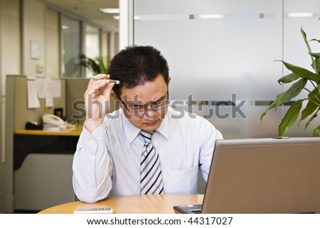 young asian business executive appears to be troubled and is thinking hard on solutions