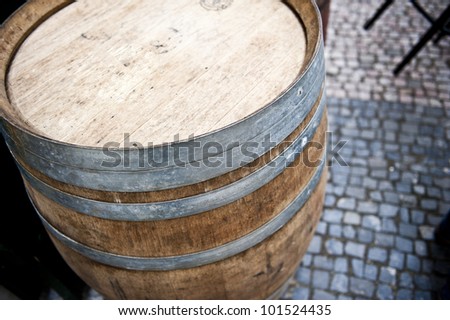 A bright shot of a beer keg on pavement outside of a restaurant or bar.