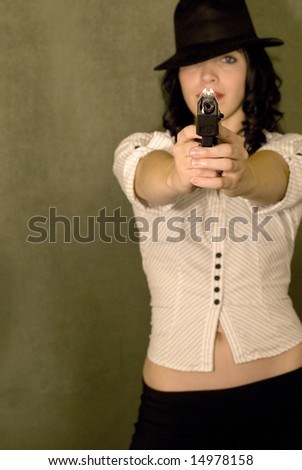 Gorgeous female model posing with a gun in a studio.