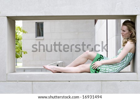 Blonde woman with no shoes sitting inside wall
