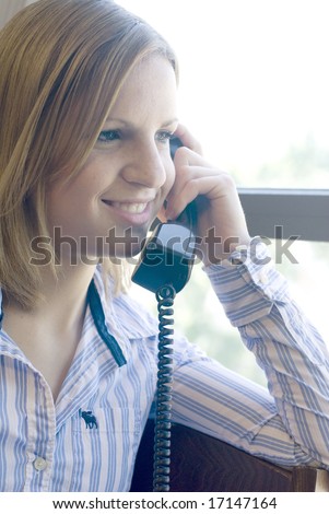 Woman with striped short smiling while holding a telephone receiver