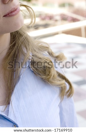 Close-up of a blonde womans hair resting on her blue collared shirt