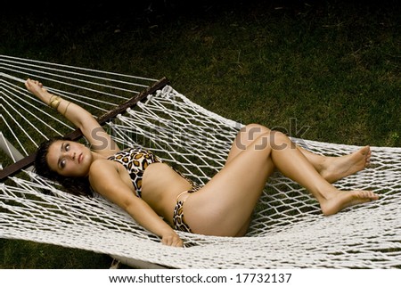 Beautiful female posing in print one-piece bathing suit in white hammock