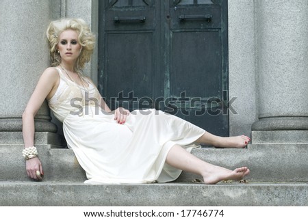 Fair skinned female with long white dress and no shoes sitting outside