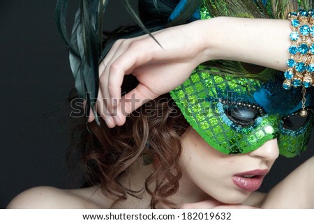 A portrait of a young brunette female model masked in a studio while looking down.