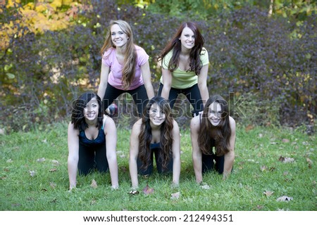 5 girls created a human pyramid on a sunny day outside.