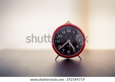 Red alarm clock on wooden old background, red vintage clock on wooden table