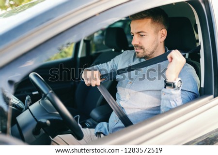 Close up of bearded Caucasian man putting seat belt while sitting in his car. 商業照片 © 