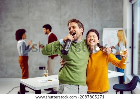 Promotion and celebration at the office. Tipsy colleagues hold the champagne, hugging, singing and celebrating promotion and success while their other colleagues in the background having fun. Foto d'archivio © 