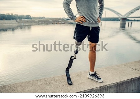 A handicapped sportsman with artificial leg standing at the quay with hands on the hips. Legs on the quay. Сток-фото © 