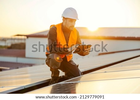 High solar energy usage. A handyman using tablet to test solar panels. 商業照片 © 