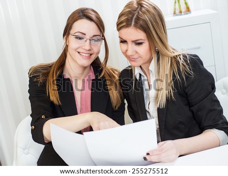 Business meeting, showing contract document, casual conversation at office, two beautiful females.