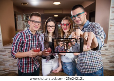 Young friends taking selfie at cafe. Shallow depth of field. Focus is on smart phone.