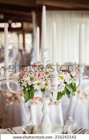 Wedding table decoration at restaurant. Shallow depth of field. Candle holder with flowers.