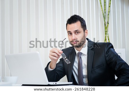 Confused businessman looking at camera, sitting at office, there is some question.