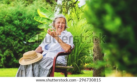 Old grandmother eating apple in park. Healthy lifestyle.